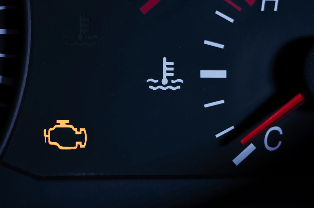 A car dashboard showing an illuminated check engine light, a coolant temperature gauge, and coolant temperature indicator.